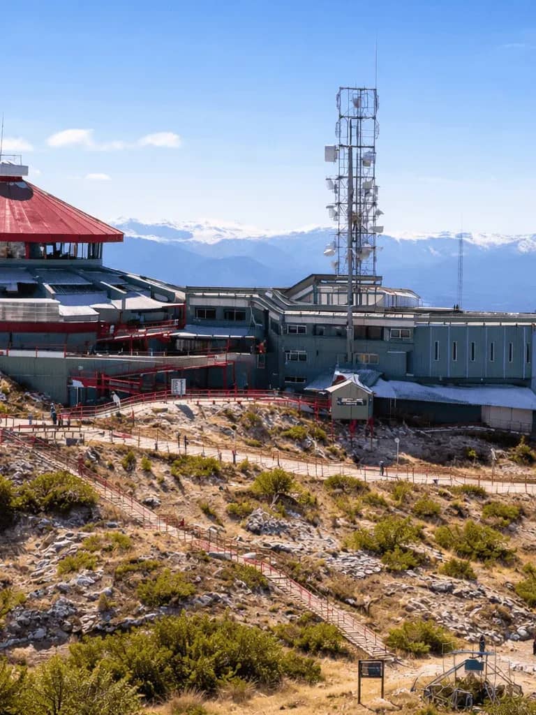 View of the Teleférico Cerro Otto Mountain Complex, surrounded by forest and under a clear sky.