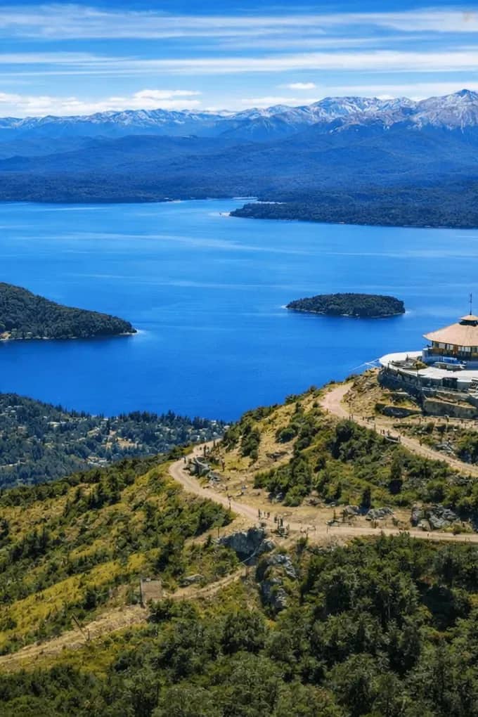 Vista panorâmica do topo do Cerro Otto com a confeitaria giratória e o Lago Nahuel Huapi rodeado por montanhas e florestas, Bariloche.