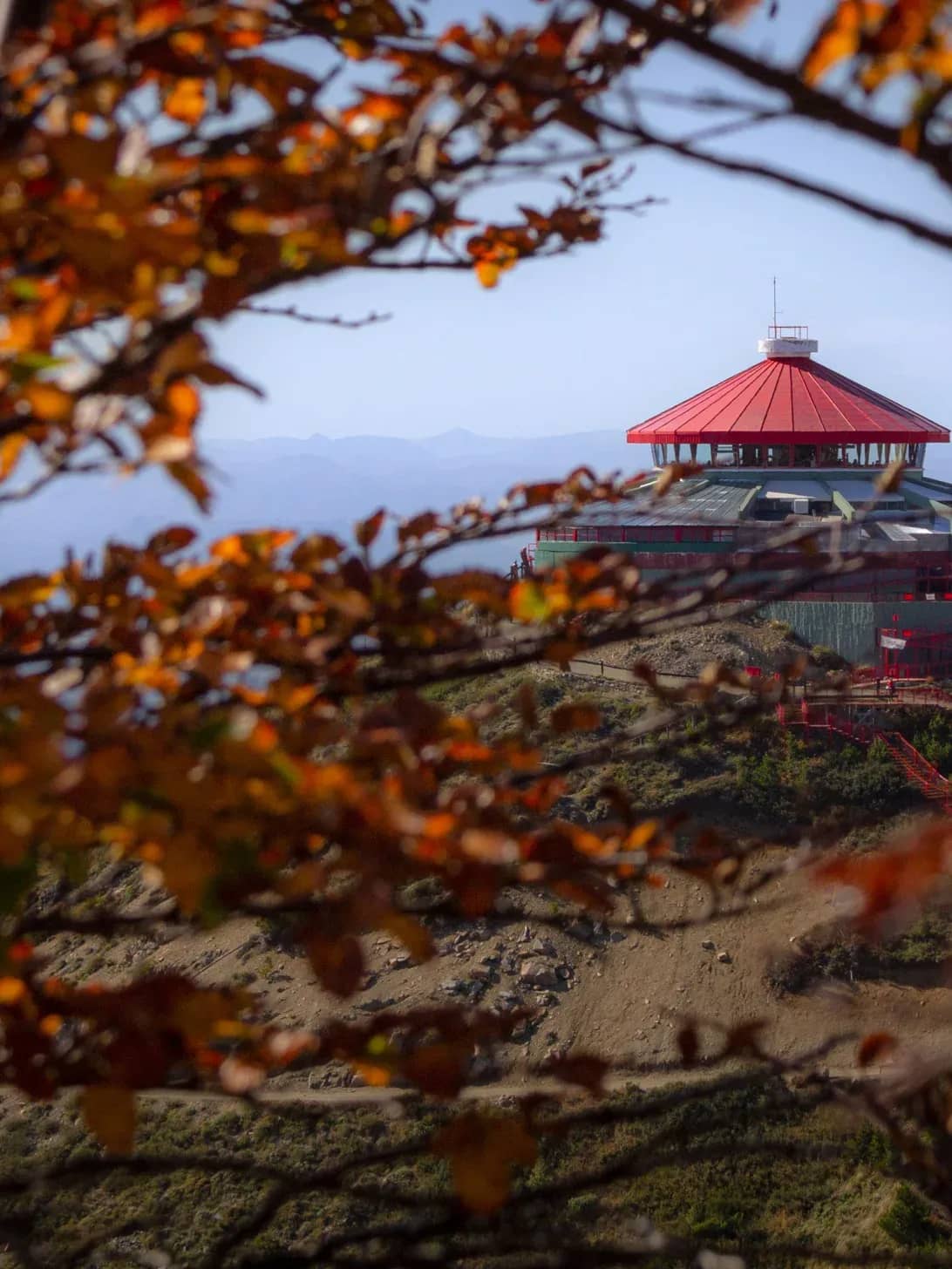 View of the Revolving Confectionery of the Teleferico Cerro Otto framed by the autumn foliage of the Bariloche forest.