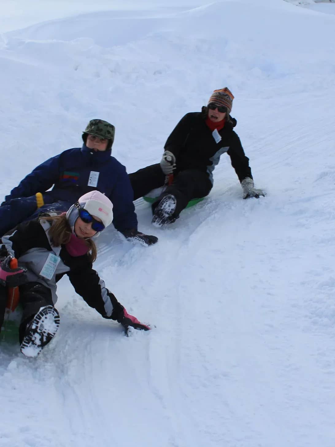Three adults sliding down a toboggan run