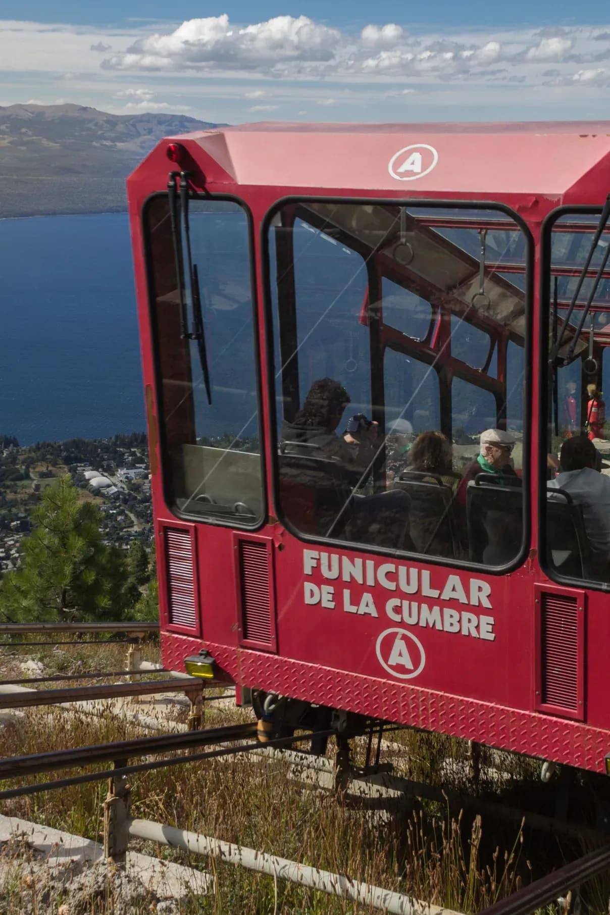 Close-up of the summit funicular with people inside as it descends with Lake Nahuel Huapi in the background