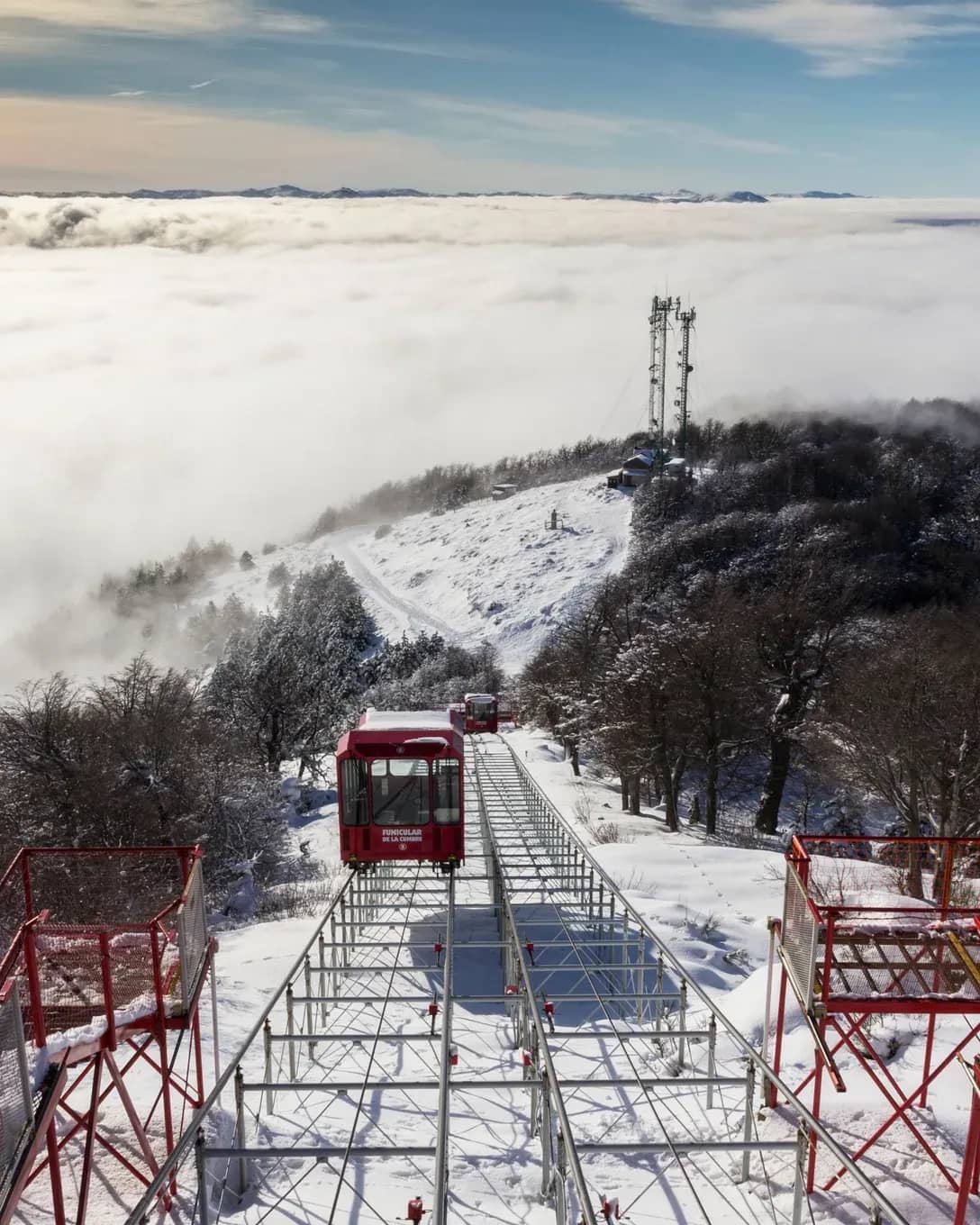 Top view of the funicular with a snowy background and a blanket of clouds in the background
