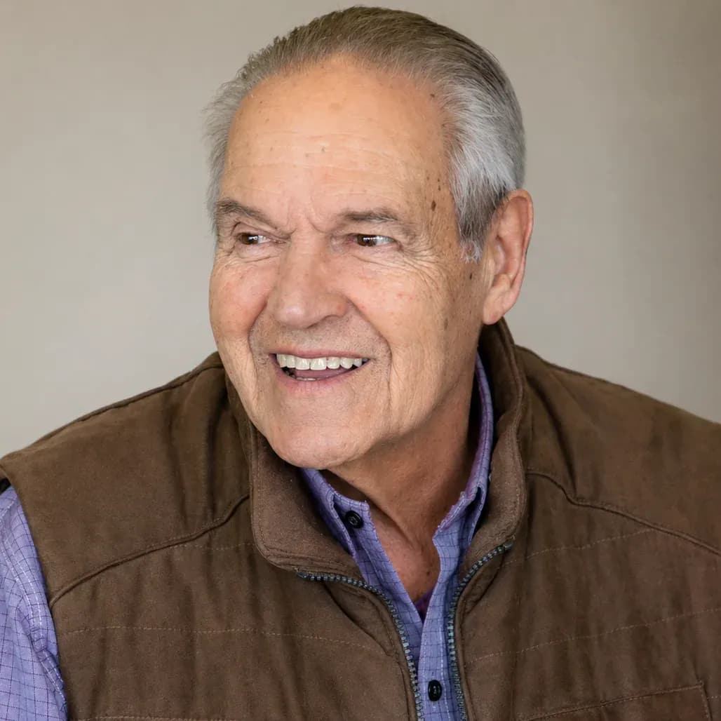 Portrait of the Executive Director of Teleférico Cerro Otto and current President of the Fundación Sara María Furman, wearing a brown vest and a checkered shirt, in an indoor setting with a neutral background.