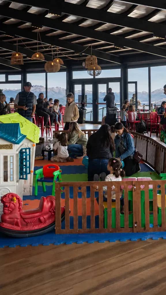 Praça de alimentação com pessoas comendo e admirando a vista panorâmica do Lago Nahuel Huapi.